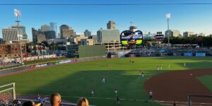 A Group Of People Sitting Around A Baseball Field